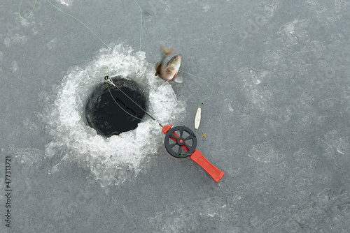 red fishingrod next to a hole in the ice and a jumping perch