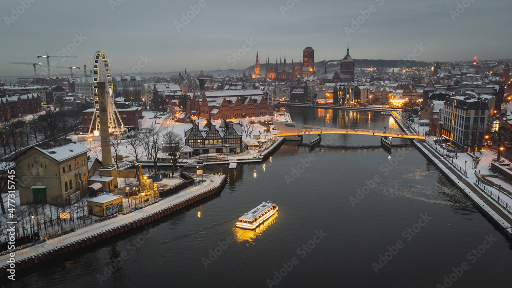 Aerial view of Gdańsk, the footbridge, the Motława River and a passing ship in winter scenery.