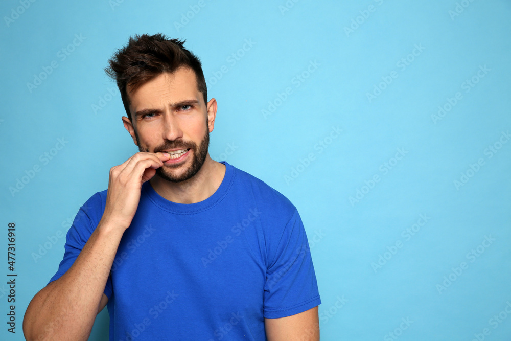 Fototapeta premium Man biting his nails on light blue background. Space for text