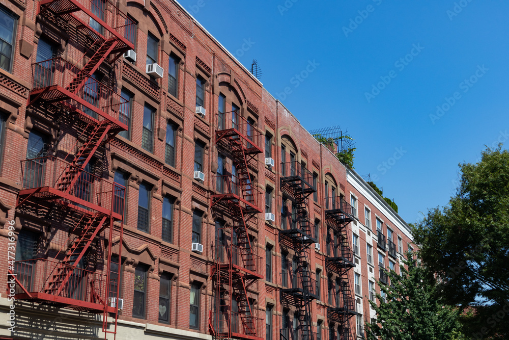 Row of Colorful Old Brick Apartment Buildings in Harlem of New York City with Fire Escapes