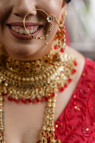 Indian bride dressed in Hindu red traditional wedding clothes sari embroidered with gold jewelry Traditional Ethnic Asian Bridal Costume and Heavy Jewellery Happy smile on the face of Indian Bride 