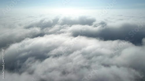 Aerial shot of flying over a layer of soft clouds at dawn