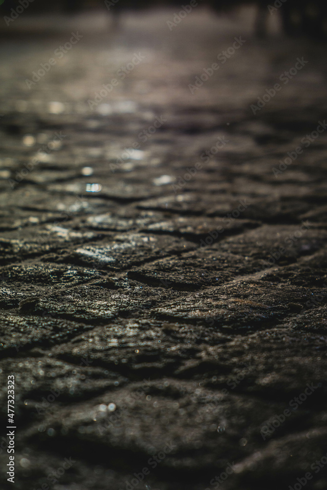 Old stone tiles, on the background of a house with illumination in defocus, photo at night Old stone tiles, on the background of a house with illumination in defocus, photo at night