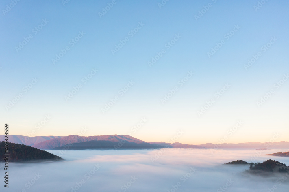 High mountain peaks with trees covered with thick fog