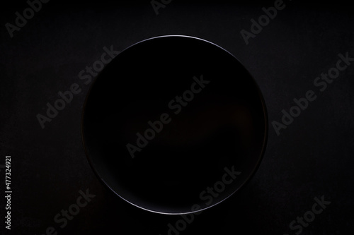 leerer schwarzer Teller mit Blick von oben auf schwarzem Hintergrund photo