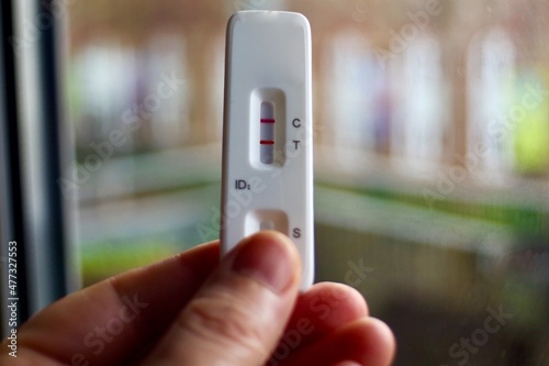hand holding up a positive lateral flow test for Covid 19
