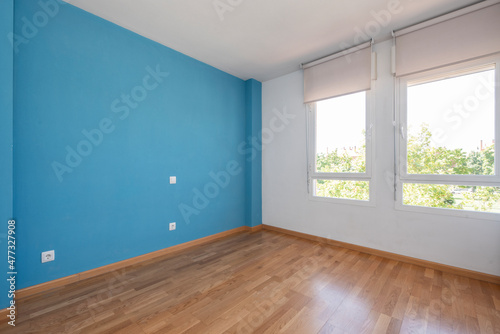 Empty room with blue wall  oak flooring and large windows