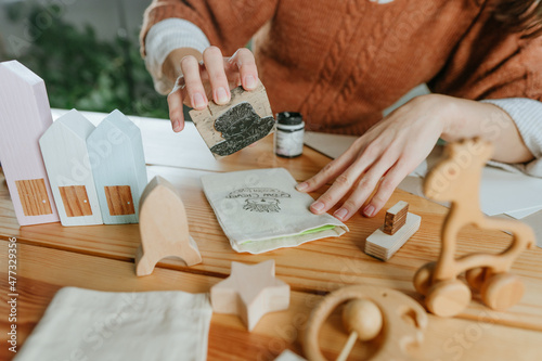 Young woman putting a stamp on a linen bag packing purchase