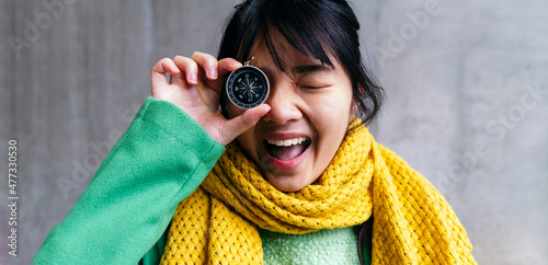 Cheerful woman holding navigational compass in front of eye