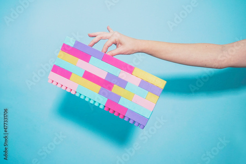 Arm of woman holding colorful pastel colored toy blocks against blue background photo