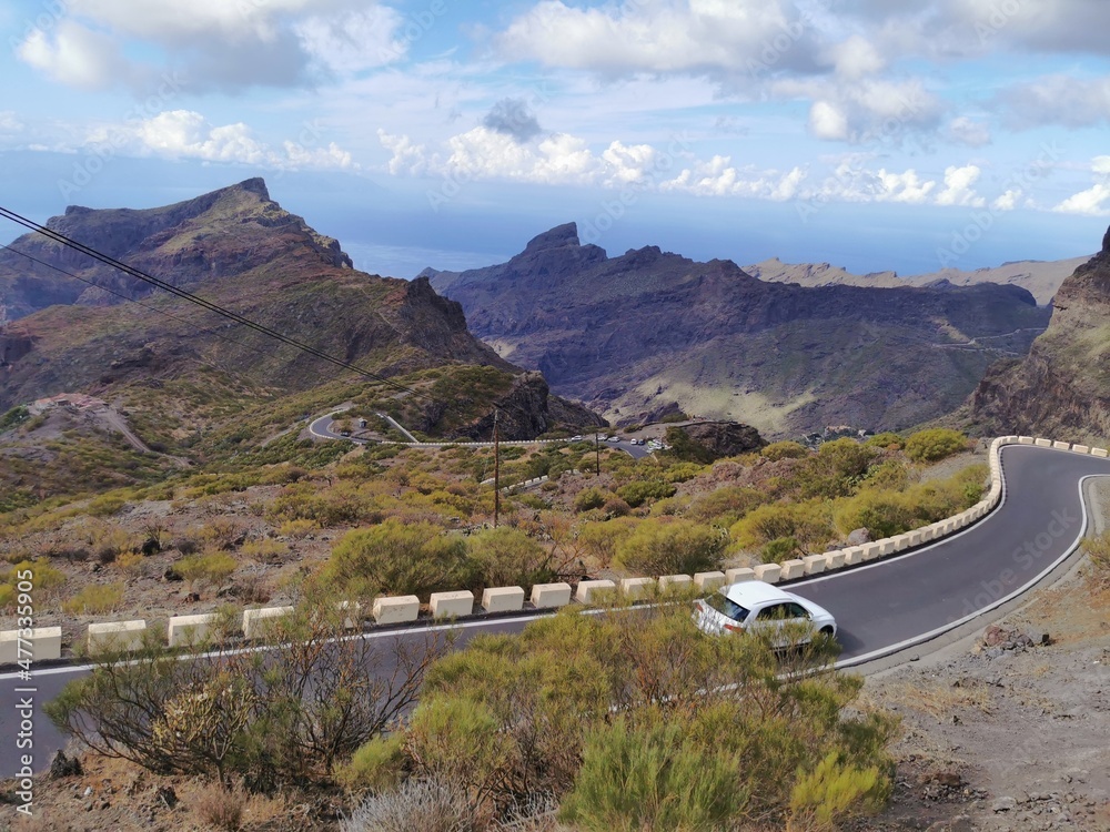 Serpentine road with the white car on it. Fabulous Masca village in mountain gorge the most visited tourist attraction of Tenerife, Spain