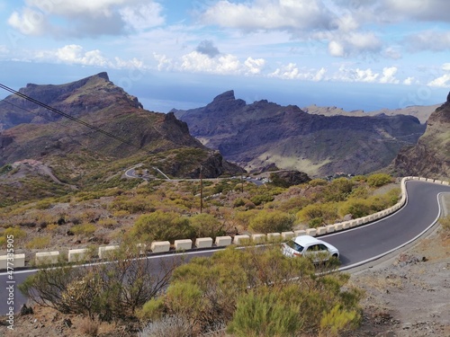 Serpentine road with the white car on it. Fabulous Masca village in mountain gorge the most visited tourist attraction of Tenerife, Spain