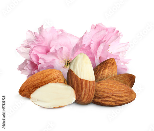 Tasty almonds and pink flowers on white background