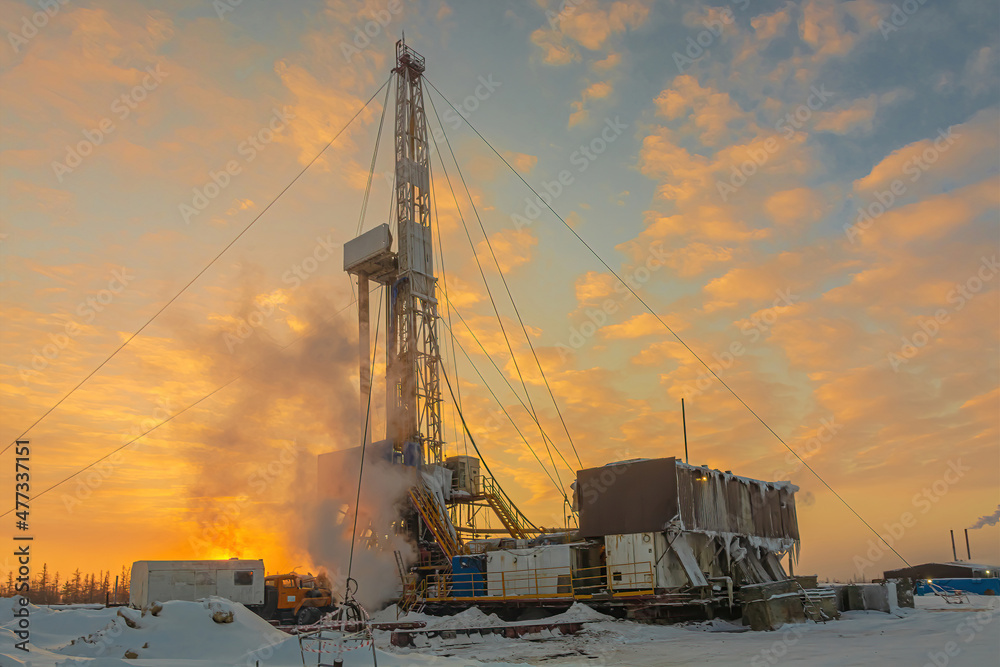 Drilling wells in the winter at an oil and gas field in the Arctic. Polar day with textured beautiful sky. Steam puffs for heating equipment