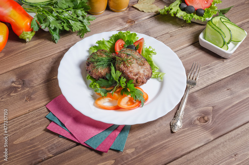 Fried meat cutlets with vegetables on a dark wooden background