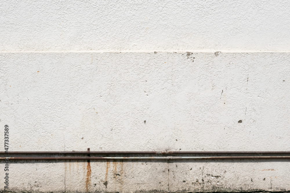 White stucco wall with rusty metal pipe White stucco wall with rusty metal pipe