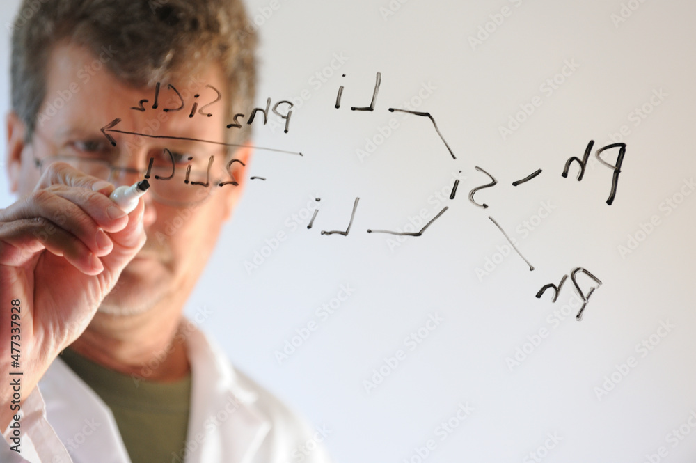 Scientist_writing_chemical_reaction_on_glass_MR Scientist_writing_chemical_reaction_on_glass_MR
