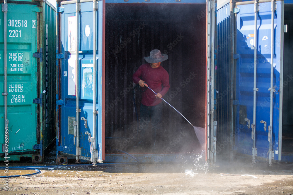 worker is cleaning container water spay gun. worker is cleaning container water spay gun.