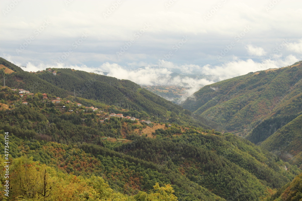 Mountain slopes in the clouds, a small village from a distance