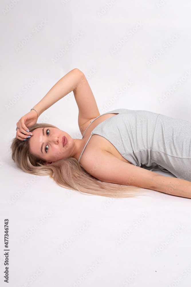 Lying young european woman with white skin isolated on grey with hand near the face