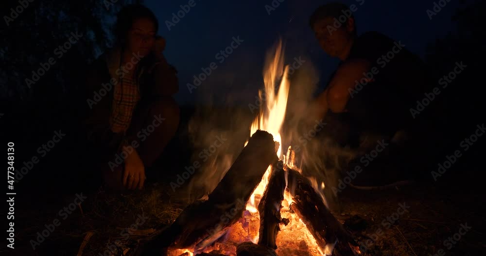 Family Sit near Campfire Watching on Fire Flame. Tourist Father Mother Child Rest on Camping Site Near Lake in Field Plains. Rural Country Countryside Scene. Summer Evening Twilight Dusk Night 4K Family Sit near Campfire Watching on Fire Flame. Tourist Father Mother Child Rest on Camping Site Near Lake in Field Plains. Rural Country Countryside Scene. Summer Evening Twilight Dusk Night 4K