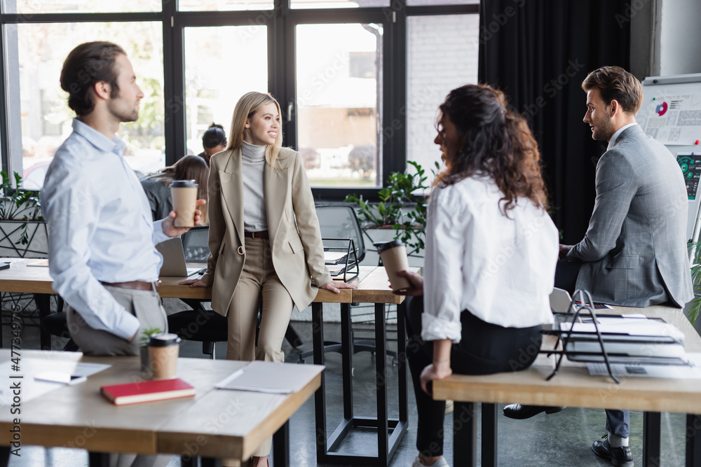 young multiethnic business colleagues with coffee to go talking in office. young multiethnic business colleagues with coffee to go talking in office.