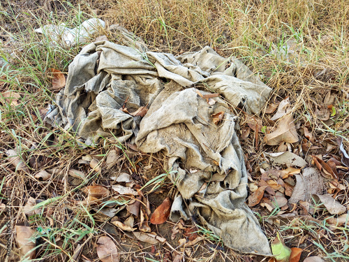 Old rags thrown in the middle of the vegetation. Environmental pollution. Disposal of clothes concept. Textile garbage in nature.