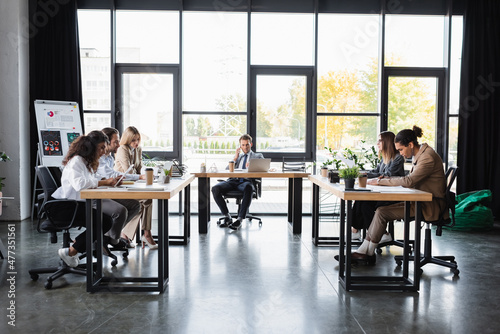 businessman talking on mobile phone during meeting with multiethnic colleagues. © LIGHTFIELD STUDIOS