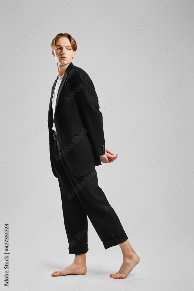 Young barefoot man in suit posing in studio
