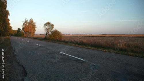 Car Vehicle Moving Along Highway Asphalt Country Road Near Field. Autumn Season. Evening Sunset Sun Sunshine. Europe Rural Scene Background. 2x Slow motion 60fps 4K photo