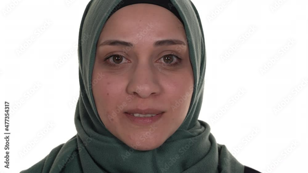 Close up of a muslim woman's face smiling at the camera. Isolated on a white background.