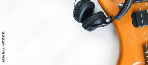 Portable black headphones and bass guitar on white background.