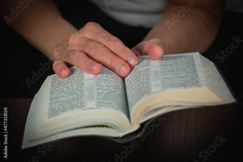 An older woman (old woman) reads a book, the Bible in transliteration in Russian. An elderly lady and her hands.