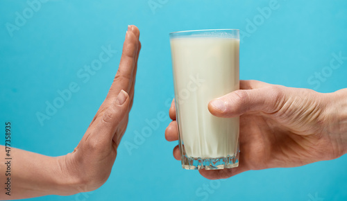 Lactose intolerance. Glass of milk and hand showing stop. photo
