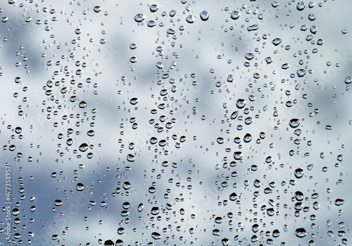 Raindrops on a foggy window behind which is a cloudy sky