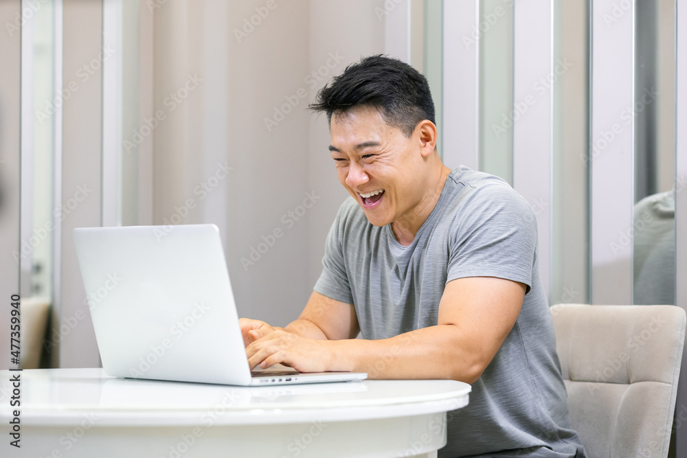Smiling young freelance man using laptop studying online work from home, happy young man typing on laptop pc surfing internet looking at screen enjoying remote work sitting at table Smiling young freelance man using laptop studying online work from home, happy young man typing on laptop pc surfing internet looking at screen enjoying remote work sitting at table