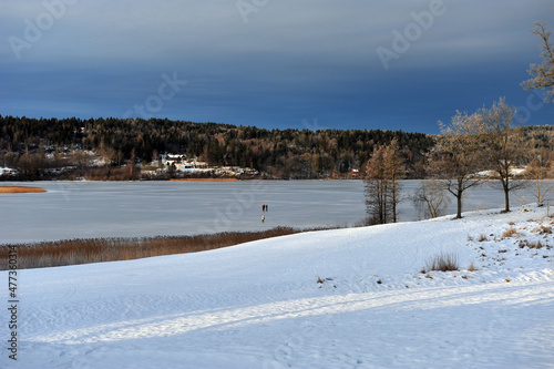 Beautiful winter scene of Borrevannet lake in Horten, Norway. Ski track in the front of image.  People skating on the lake in the background. Pretty weather on a frosty day. photo