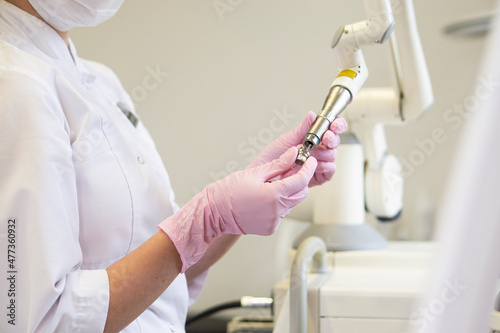 Woman doctor cosmetologist replaces the attachment on the cosmetology laser apparatus fotona in a beauty salon. Equipment for skin care and removal of popid and warts for the treatment of blood 
