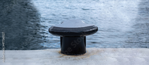фотографія Black bollard on harbor pier, sea water background, space