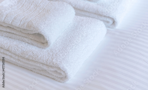 Fresh white towel on a hotel room bed, close up. Bedroom interior detail, comfort and hospitality