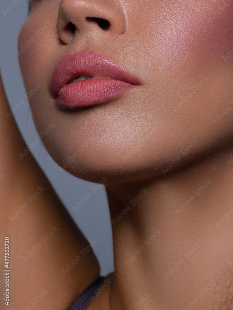 Obraz premium Cosmetics, makeup and trends. Bright lip gloss and lipstick on lips. Closeup of beautiful female mouth with natural lip makeup. Beautiful part of female face. Perfect clean skin in natural light