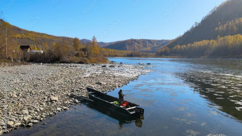 man throws a fishing rod on the bank of a beautiful wide river boat mountain autumn man throws a fishing rod on the bank of a beautiful wide river boat mountain autumn