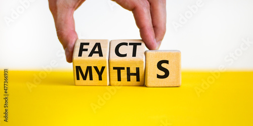 Facts or myths symbol. Businessman turns wooden cubes and changes the word myths to facts. Beautiful yellow table, white background, copy space. Business and facts or myths concept. photo