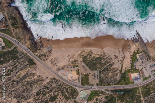 Aerial view of vehicles driving a scenic road along the wild coastline near the Ocean, Cascais, Lisbon, Portugal.
