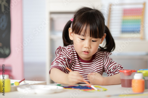 young girl painting hand made craft at home