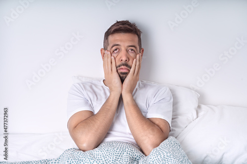 Stressed and depressed man lying in the bed. Bad mood and bad morning. photo