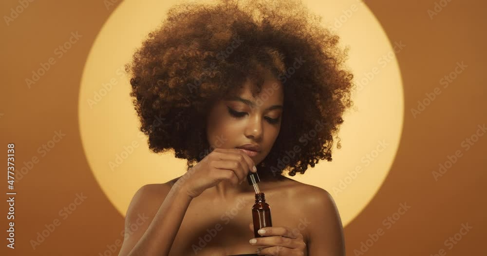 Beauty video of young african woman applying serum to her face with dropper like a part of her skin care routine