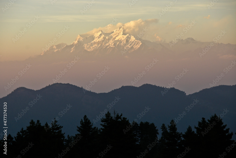 Foothills, valleys, and snow-capped peaks of Himalaya mountain range in late-afternoon light and mist, viewed from Daman, Nepal