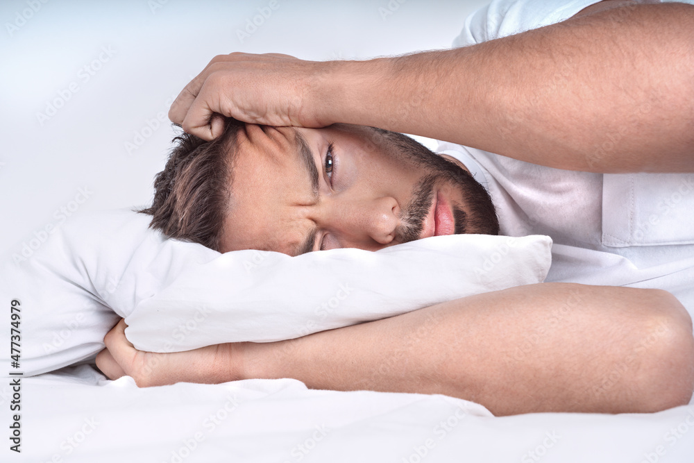 Man with depressive disorder lying on the pillow in the bed. Depressed man with negative thoughts. Man with depressive disorder lying on the pillow in the bed. Depressed man with negative thoughts.
