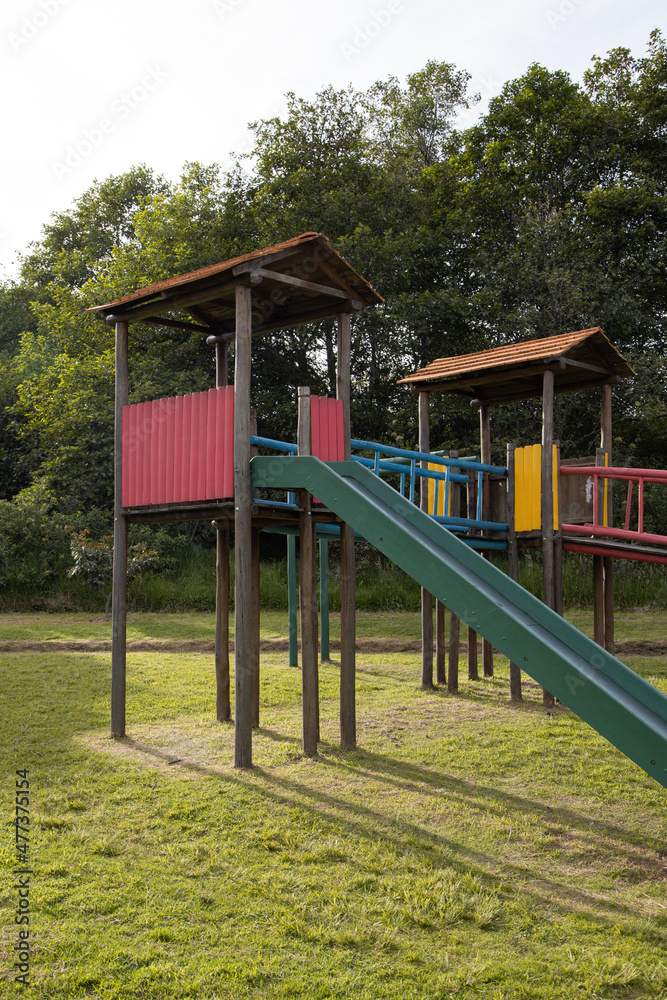 sunny day in a park surrounded by nature and wooden playground with slide, colorful entertainment place, lifestyle sunny day in a park surrounded by nature and wooden playground with slide, colorful entertainment place, lifestyle